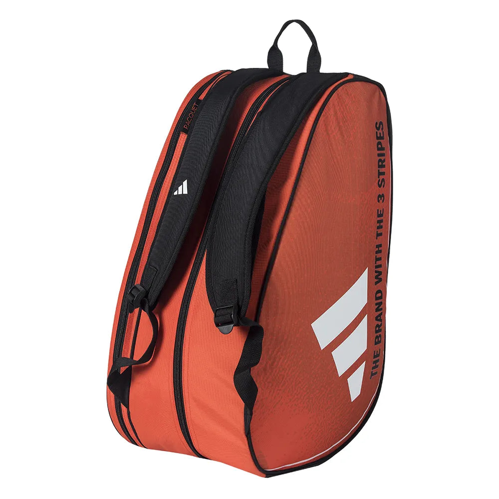 An orange adidas Control 3.4 Padel Racket Bag with white logo, "THE BRAND WITH THE 3 STRIPES" text on the side, modern graphics, two shoulder straps, top handle, and a dedicated racket compartment.