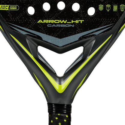Close-up of the adidas ADIDAS Arrow Hit Carbon 2026 Padel Racket, featuring a black and yellow design, triangular throat, grip tape handle, and circular holes on its carbon face.
