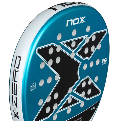 Close-up of the NOX X-Zero Blue Padel Racket by NOX, designed for beginners and offering excellent control, showcasing a large "X" design, white text, and multiple holes on its blue and black surface.