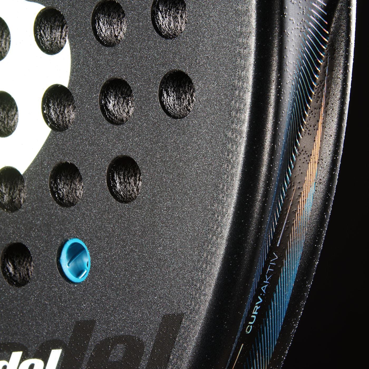 Close-up of the Bullpadel Vertex 05 Comfort 2026 Padel Racket (Black/Blue) surface, featuring circular holes, a white logo, blue insert, "CURV AKTIV" on the edge, and textured Fibrix fibre detail. Brand: Bullpadel.
