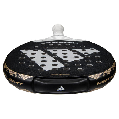 Close-up of a lightweight ADIDAS Metalbone Team Light 3.4 Padel Racket in black and white, featuring a textured surface with circular holes. Designed for advanced players, the handle is white-wrapped, with adidas logos and "Metalbone Team Light" on the edge.