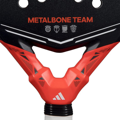 Close-up of the adidas Metalbone Team 2026 Padel Racket - Black / Red, showing "METALBONE TEAM" text, geometric patterns, a white adidas logo above the handle, and Spin Blade Gritt technology for enhanced performance.