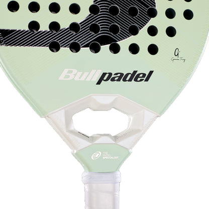 A detailed view of the Bullpadel Elite 02 2027 Padel Racket showcases its light green color with black perforations, a signature, and a white grip. The teardrop-shaped head in a hybrid design displays the Bullpadel logo along with “The Padel Specialist” text near the handle.