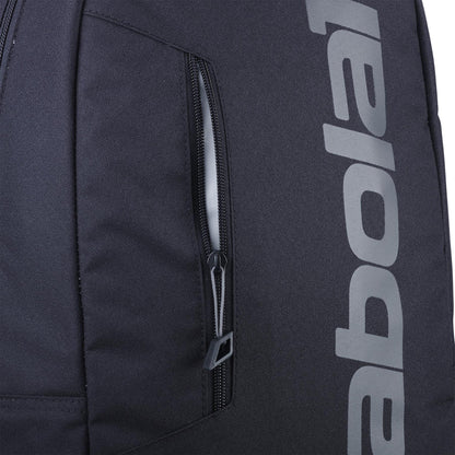 Close-up of the Babolat Court Lite Padel Backpack - Black by Babolat, showing a vertical zippered pocket and part of "babolat" in large light gray letters on the side; features a dedicated racket compartment for convenience.