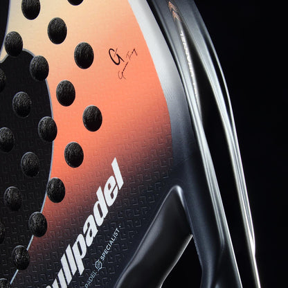 Close-up of the Bullpadel Elite W 2026 Padel Racket by Bullpadel, a lightweight, high-performance padel racket in black and white with textured holes and signature branding, shown against a dark background.