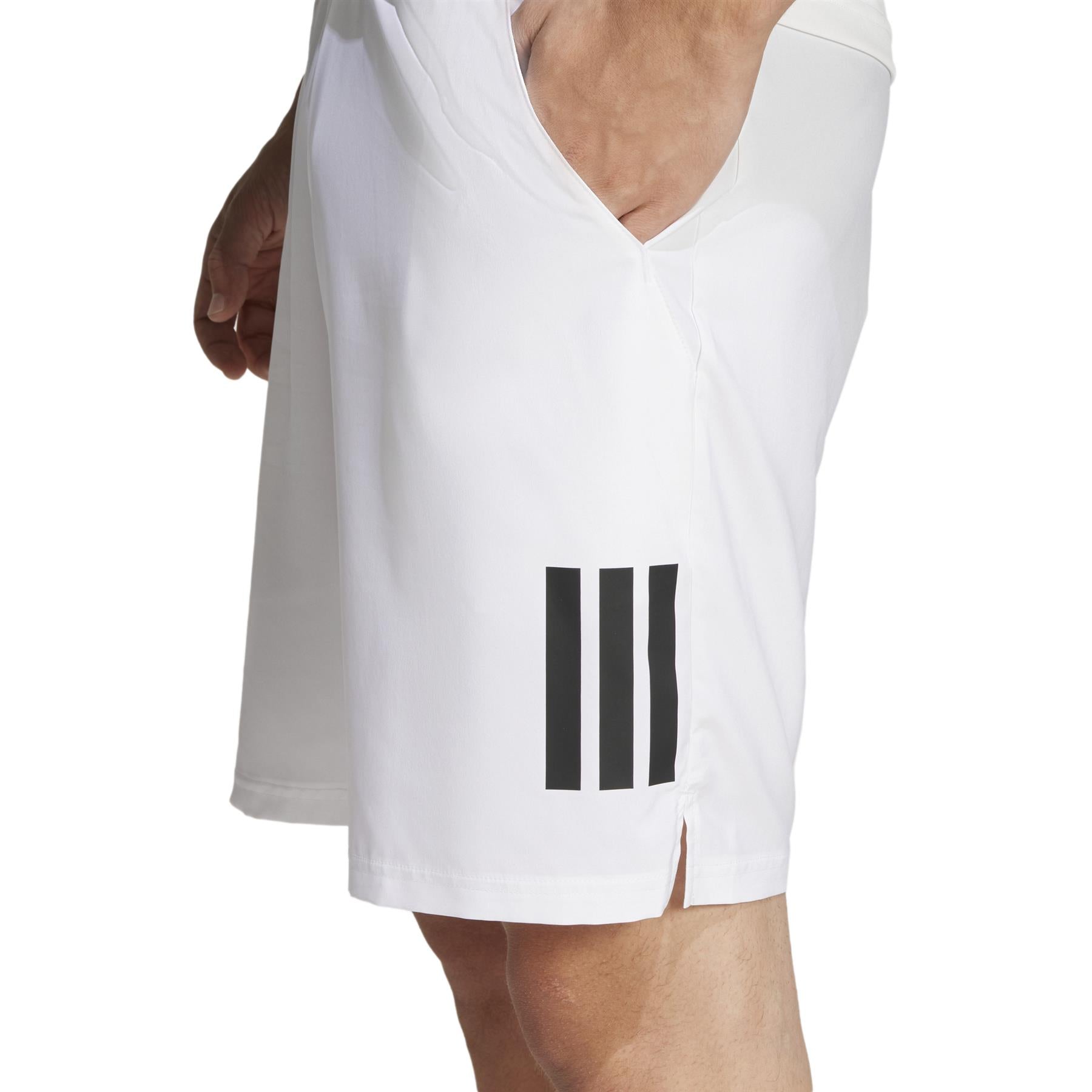 Close-up of a person in ADIDAS Men's 3 Stripe Padel Shorts - White, adorned with three black vertical stripes and enhanced by AEROREADY technology. A small slit at the hem adds comfort, while the individual's hand rests casually on their hip.