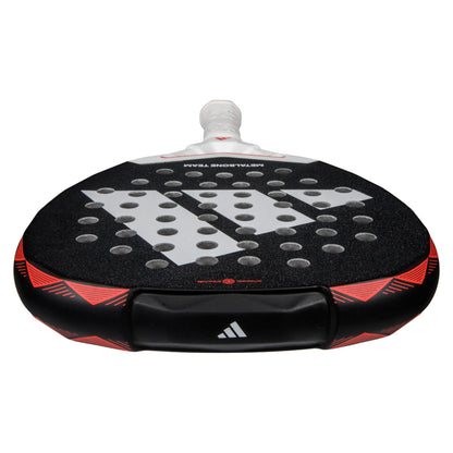 A close-up of an ADIDAS Metalbone Team 3.4 Padel Racket - Black/Red, featuring a textured surface and circular holes. Designed for advanced players, it boasts a white handle, geometric patterns, and the adidas logo in striking black and red tones.