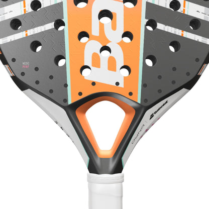 Close-up of a modern padel racket from Babolat, featuring a white and pink color scheme. The design includes the recognizable Babolat brand logo, Dyna Energy technology, and a triangular cut-out near the handle. The Carbon Flex surface boasts multiple holes and text details for enhanced performance.