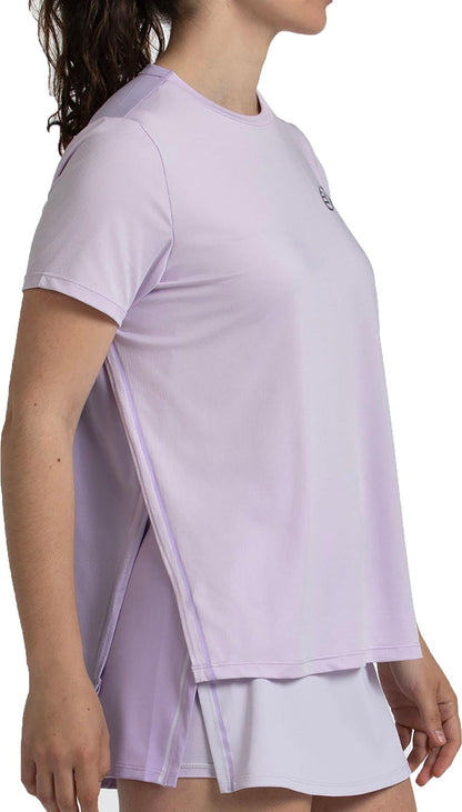 Woman in a loose-fitting Bullpadel Picase Women's Padel T-Shirt in pastel lilac, shown from the side with her face mostly out of frame. The top features side slits and a relaxed fit, paired with matching shorts.