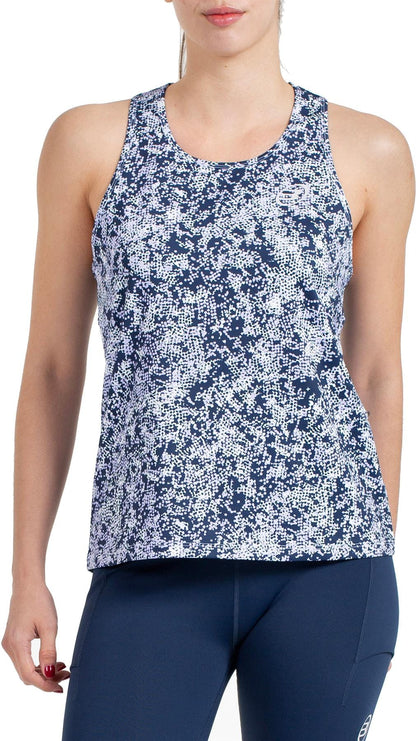 A woman stands against a white background wearing the Bullpadel Pilme Women's Padel Tank Top in Deep Ocean and navy leggings, showcasing stylish and breathable sportswear from Bullpadel.