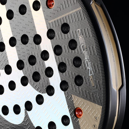 Close-up of the Bullpadel Neuron 02 2026 Padel Racket in black and gold, showcasing its hybrid shape, textured surface, circular holes, metallic gold accents, and bold Bullpadel branding for a professional look.
