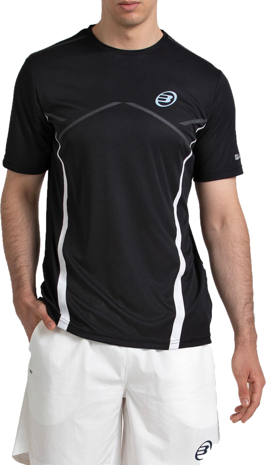 A man in a Bullpadel Cabore Mens Padel T-Shirt - Black and white shorts stands with one hand in his pocket.