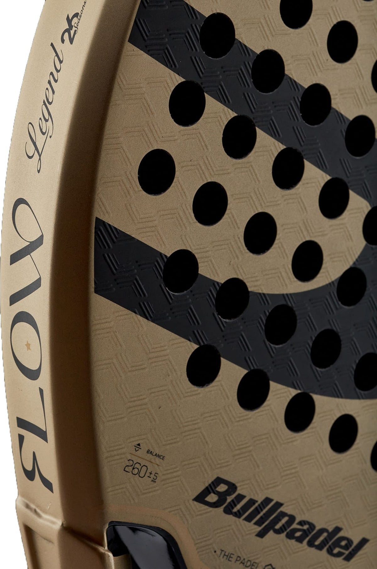 Close-up of a gold and black Bullpadel Flow 2027 padel racket, featuring the Bullpadel brand name on the edge, a diamond-shaped head, round holes, and a 3D Grain surface for enhanced grip. Balance and weight details are printed near the bottom.
