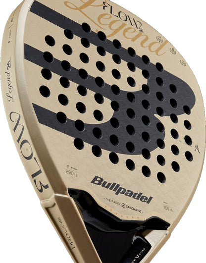 Close-up of the Bullpadel Flow 2027 padel racket by Bullpadel, highlighting its beige color, black circular holes, and the word “Legend” displayed in bold script across the upper face. This diamond-shaped racket features a 3D Grain surface for enhanced spin and control during play.