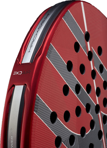 Close-up of a red and silver Bullpadel Hack 05 Comfort 2027 Padel Racket with black holes and diagonal gray stripes, showcasing detailed textures, Tricarbon 18K construction, MultiEva core, and bold Bullpadel branding elements.