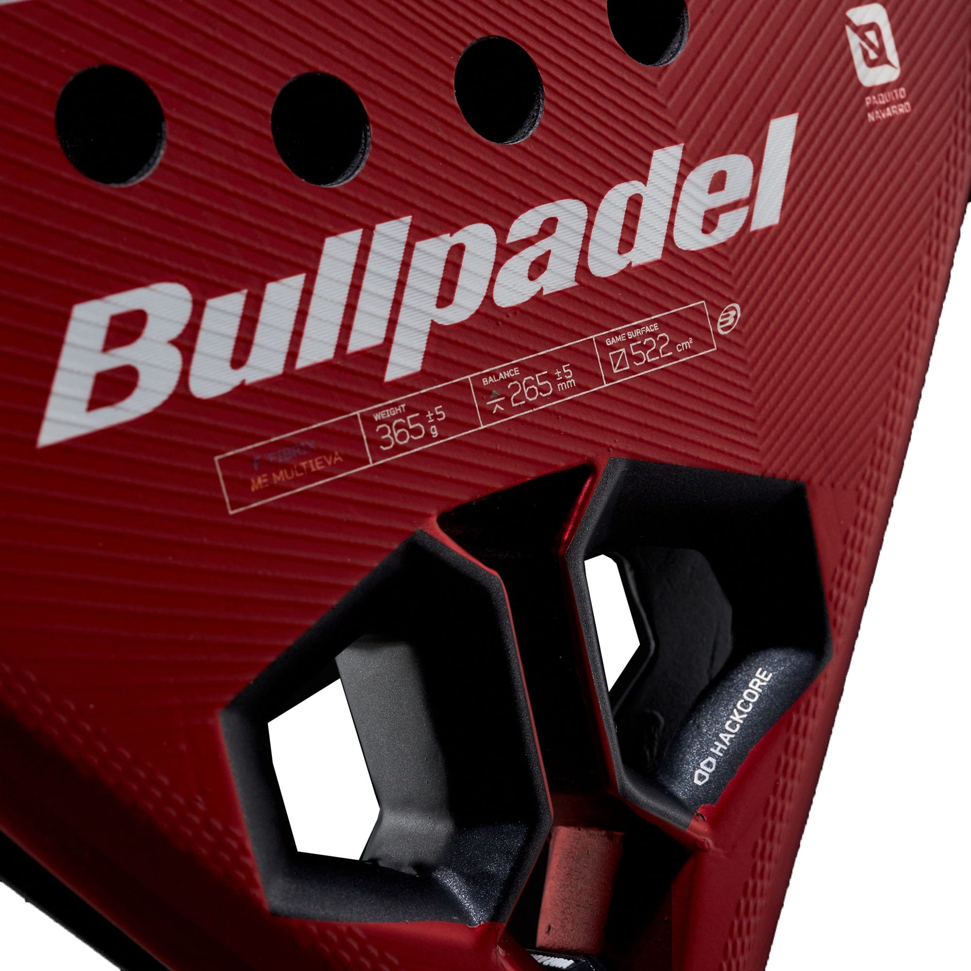Close-up of the Bullpadel Hack 05 Comfort 2027 Padel Racket in striking red, displaying the Bullpadel branding, technical details such as a MultiEva core, and two distinctive hexagon-shaped holes near the base. The racket also highlights its advanced Tricarbon 18K construction for enhanced performance.