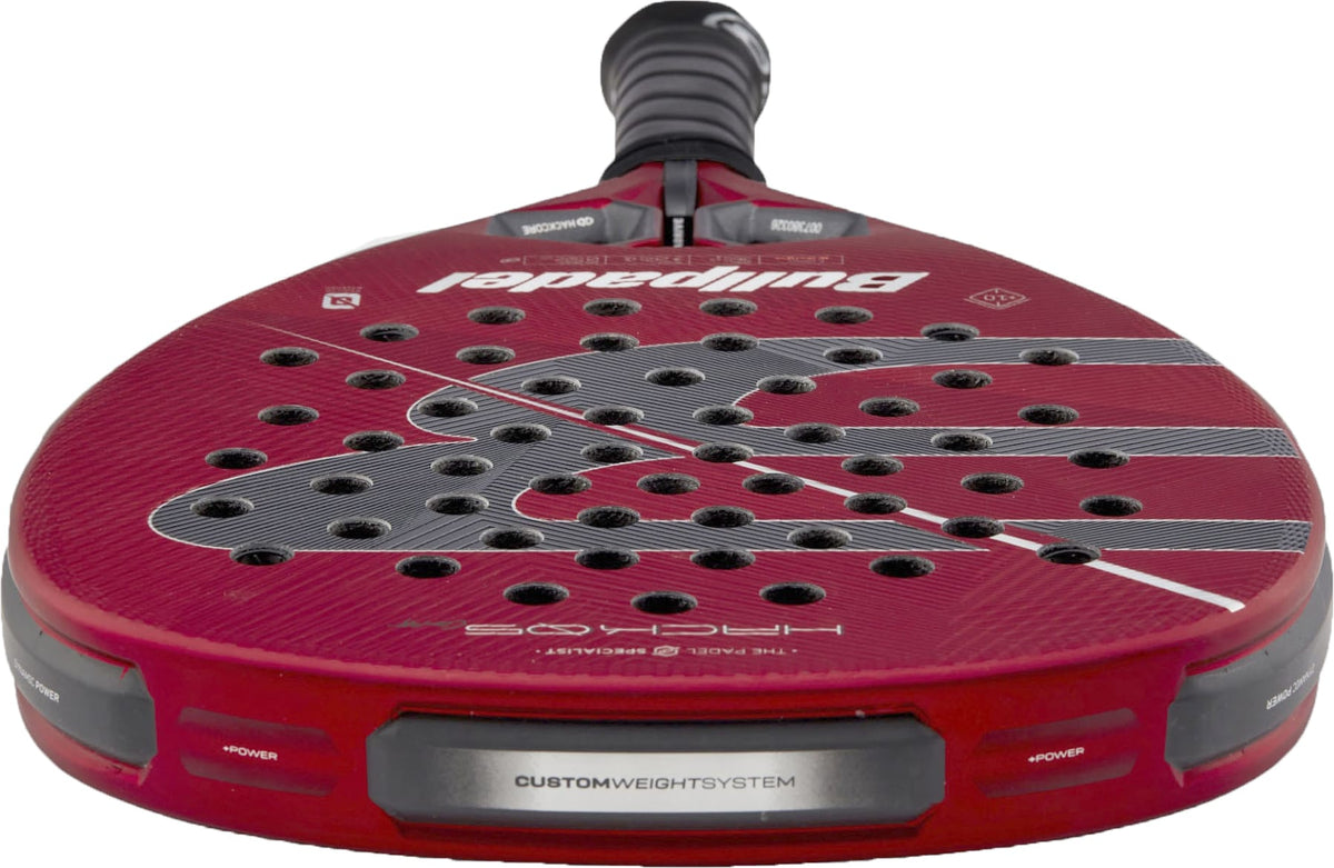A close-up view of the red Bullpadel Hack 05 Comfort 2027 Padel Racket by Bullpadel highlights its perforated face, advanced Tricarbon 18K construction, custom weight system, and textured surface details, all featuring a responsive MultiEva core.