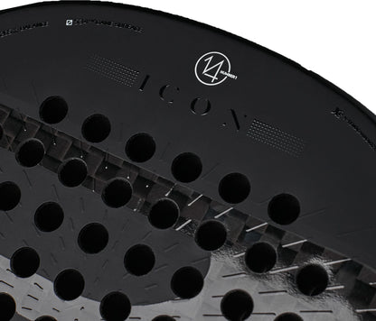 Close-up of a black Bullpadel Icon 2027 Padel Racket with round holes, highlighting the word “ICON” and a circular Bullpadel logo near the top edge. Constructed with X-Tend Carbon 12K and a MultiEva core for superior performance.