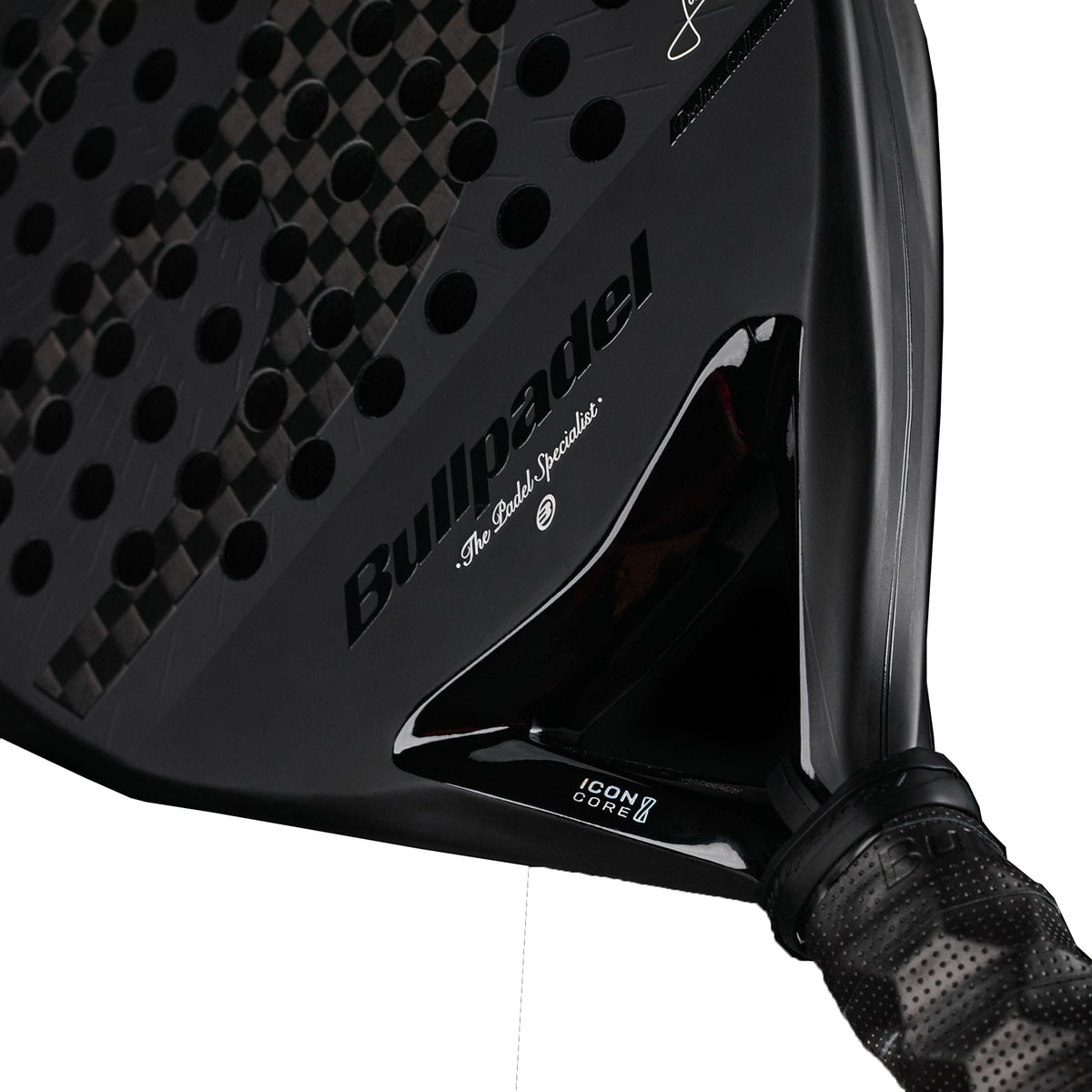 A close-up shot of the Bullpadel Icon 2027 Padel Racket displays its textured black surface, iconic Bullpadel logo, and a black-gripped handle. The design showcases X-Tend Carbon 12K detailing, “Icon Core” branding, and features an advanced MultiEva core from Bullpadel for superior performance.