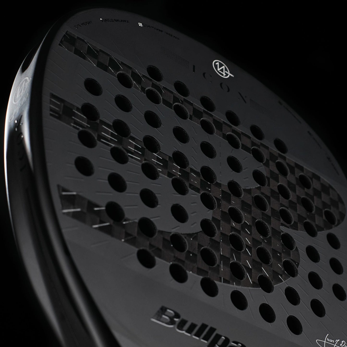 A close-up of the Bullpadel Icon 2027 Padel Racket showcases its dark design with round perforations, highlighted by a subtle bull motif and the Bullpadel logo against a black backdrop. Engineered with X-Tend Carbon 12K construction and a MultiEva core, this racket delivers enhanced performance.