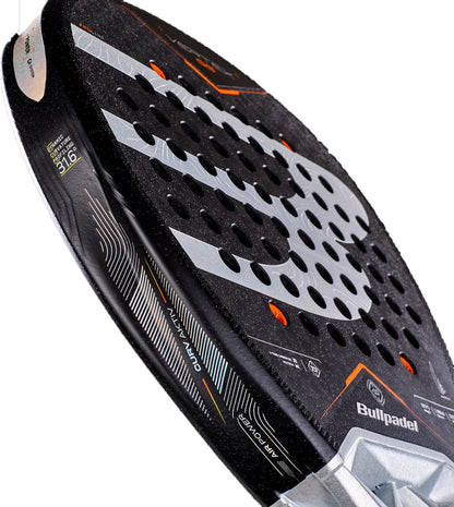 A detailed view of the Bullpadel Vertex 05 2027 Padel Racket by Bullpadel, showcasing its sleek black design with orange and silver accents, circular perforations on the face, X-Tend Carbon 12K technology, and textured grip edges—a preferred choice of Juan Tello.
