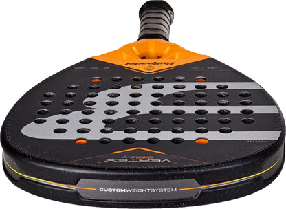 A close-up of a black and orange Bullpadel Vertex 05 Comfort 2027 padel racket with a perforated surface, showing the handle and custom weight system label. Designed for intermediate and advanced players, this model features innovative Fibrix technology for enhanced performance.