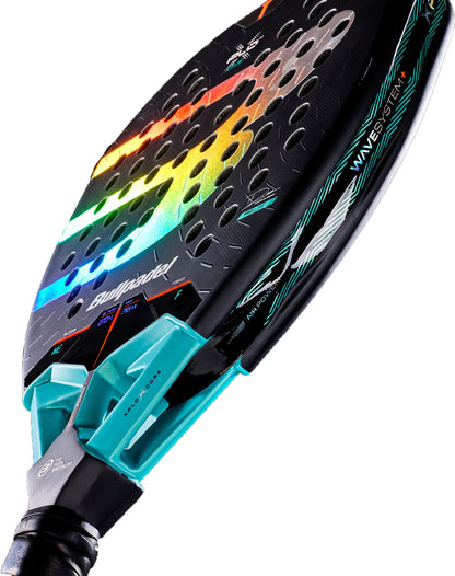 A close-up of the Bullpadel Xplo Comfort 2027 Padel Racket showcases its black frame with a vibrant rainbow gradient design, teal accents, and a textured Fibrix surface. The racket features multiple aerodynamic holes and modern elements such as an advanced MultiEva core and distinctive Bullpadel branding.