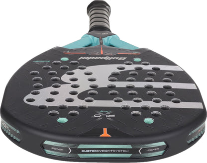 A close-up of the Bullpadel Xplo Comfort 2027 Padel Racket by Bullpadel in black with teal and gray accents, highlighting its durable Fibrix surface, MultiEva core, multiple circular holes, and custom weight system features along the bottom edge.